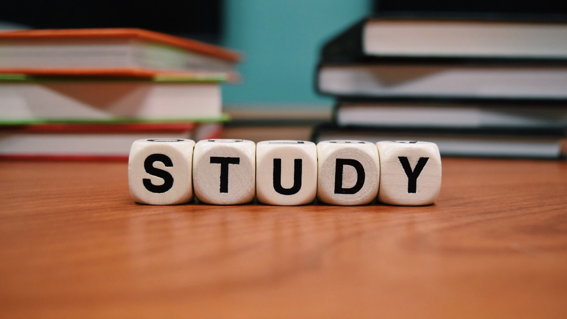 Wooden letter blocks spelling “STUDY” on a desk with stacked books in the background, symbolizing learning and skill development for building a strong online portfolio.