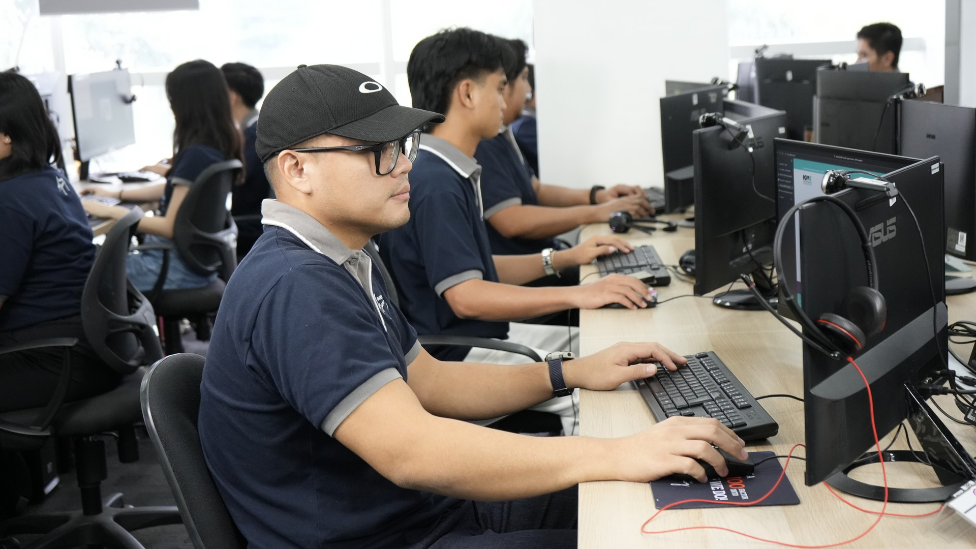 Employees working at desktop computers in a modern office, representing the digital workplace where AI tools are increasingly used.