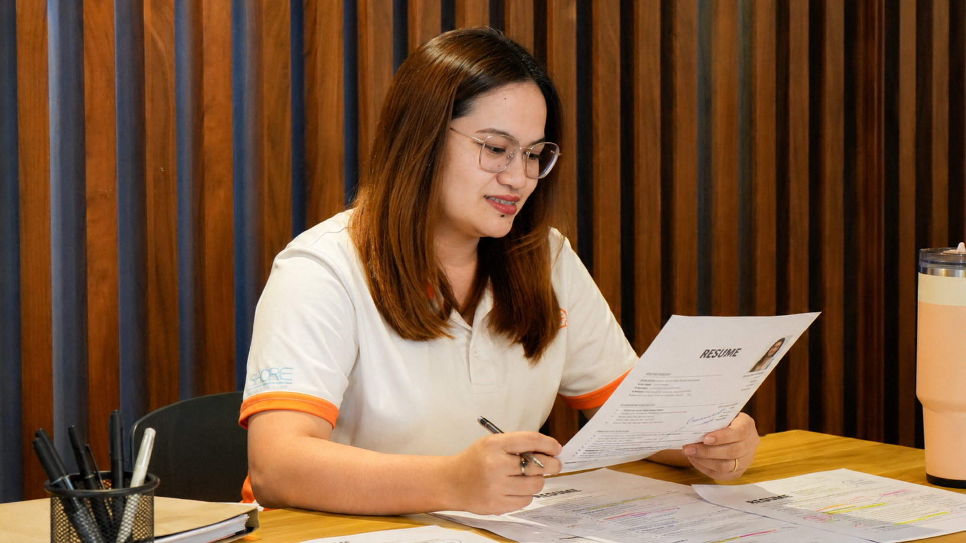 Philippine recruiter reviewing printed resumes and comparing them against job description requirements